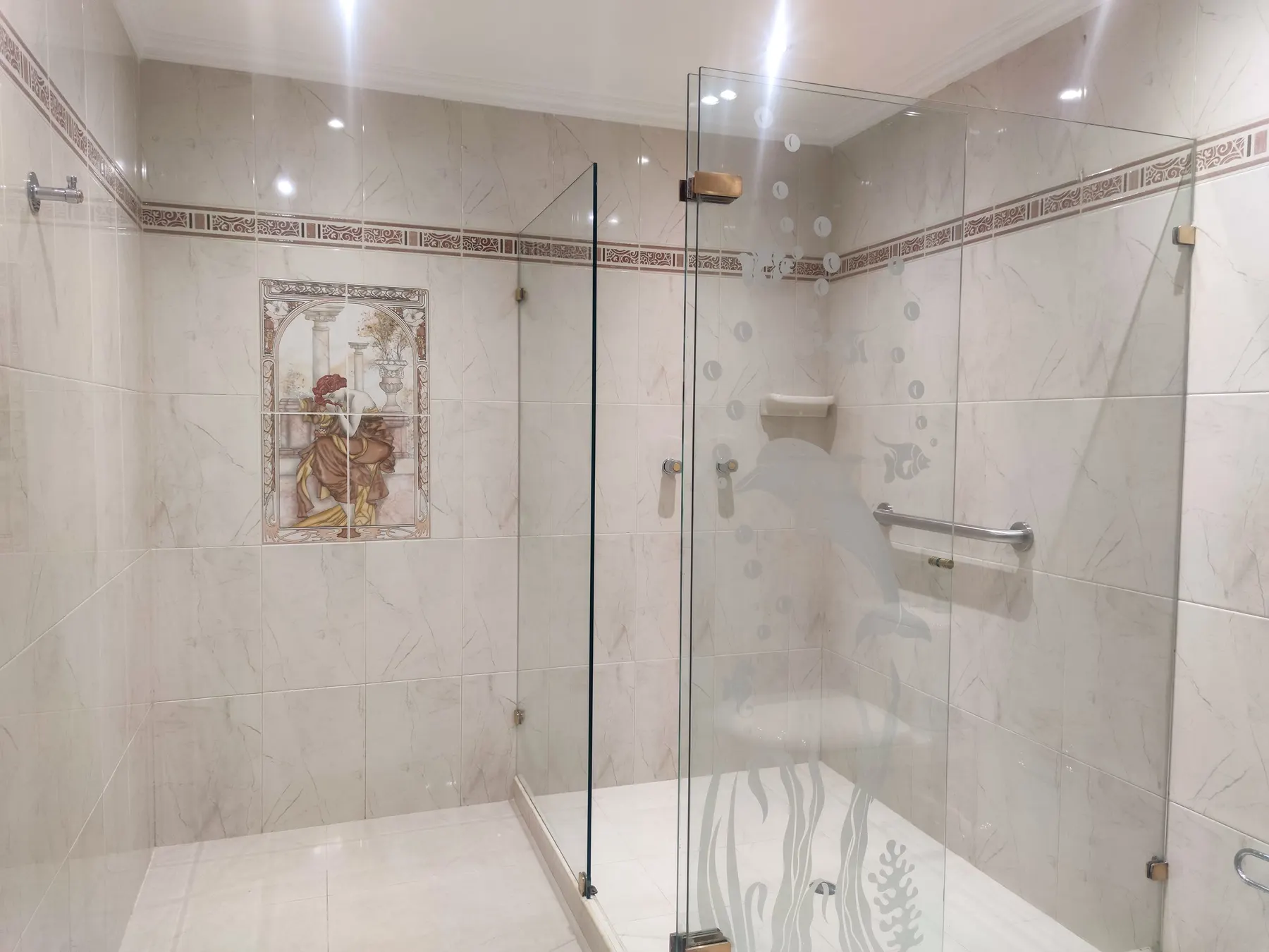 Salle de bain moderne avec douche vitrée et barre d’appui