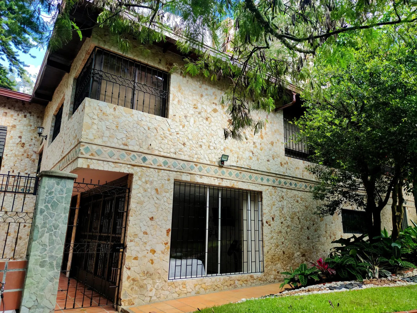 Extérieur de la maison de convalescence à El Poblado, Medellín, avec une terrasse couverte et un jardin